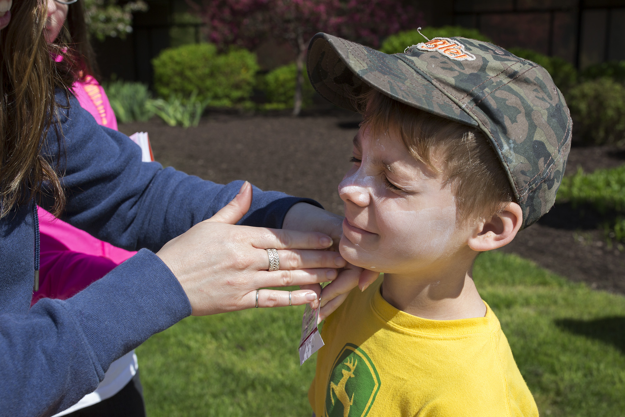 Natasha Reitz puts sunscreen on her son, Winter Reitz, 8, at the Colleges Against Cancer booth during Imagine RIT: Innovation and Creativity Festival on the Rochester Institute of Technology campus in Rochester, N.Y., May 7, 2016.  (Photo by Bridget Fetsko) #imaginerit #ritpj