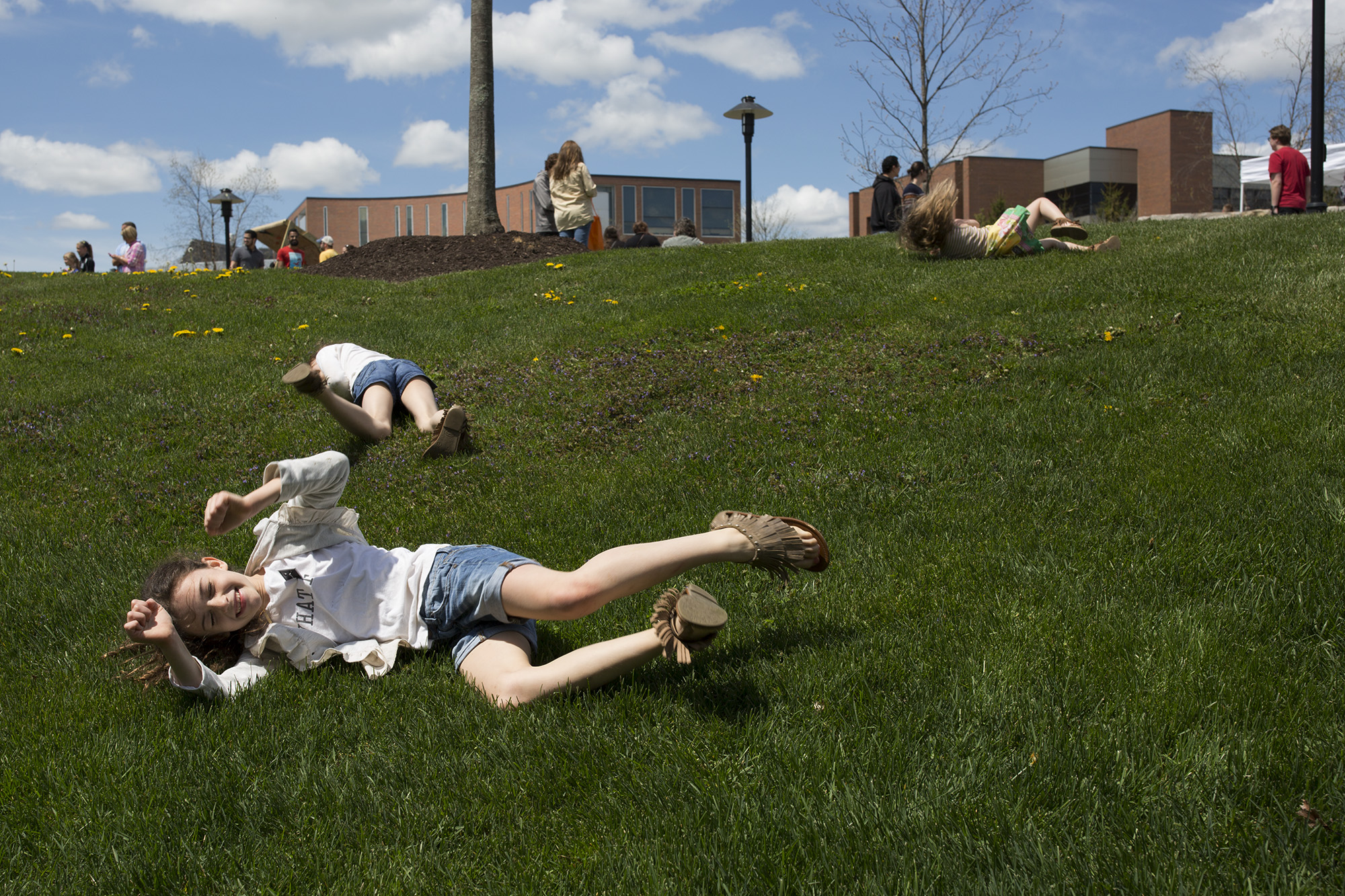 Anna Fitzgerald, 7, Rory Fitzgerald, 5, and Teagan Fitzgerald, 3, roll down a hill near Global Village during Imagine RIT: Innovation and Creativity Festival on the Rochester Institute of Technology campus in Rochester, N.Y., May 7, 2016. (Photo by Bridget Fetsko) #imaginerit #ritpj