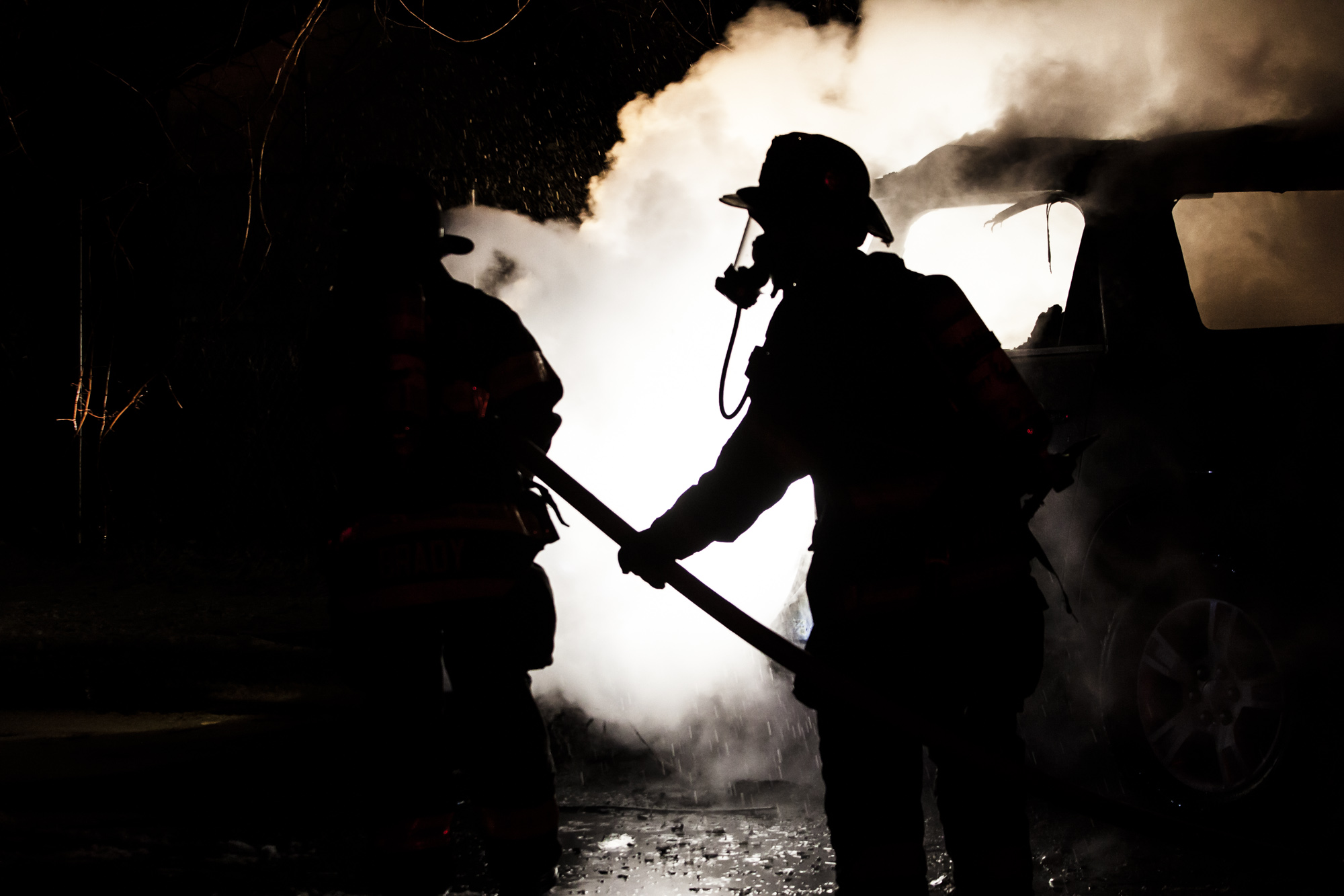 Rey Palacios feeds hose to Antoine Brady at a suspected arson in the parking lot of the UAW off Dewey Avenue just after midnight on the morning of January 24th 2013 in Rochester NY.