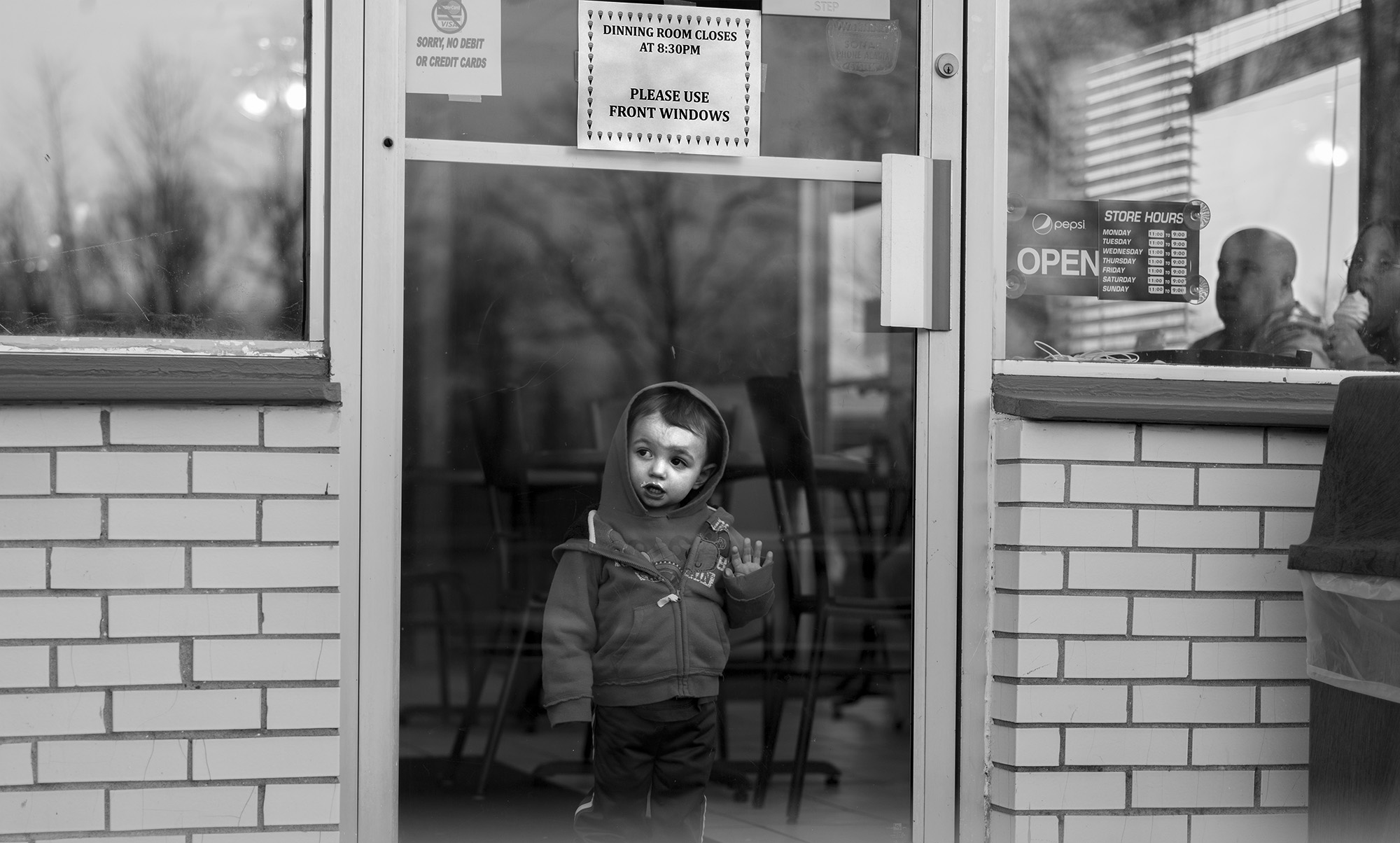 A child presses up against the door of Peppy's Too, a hamburger and ice cream stand just outside of Waterloo, NY, after finishing his ice cream.