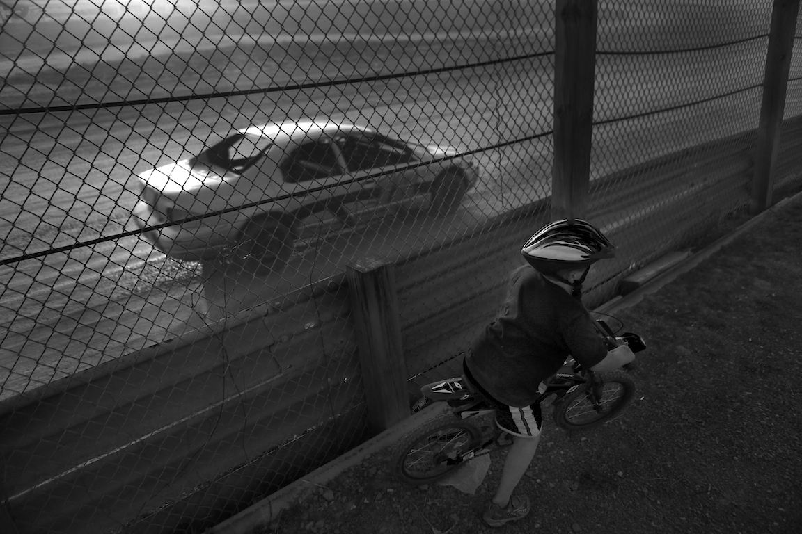 A child pretends to race along side a modified car racing at Paradise Speedways in Geneva, NY.