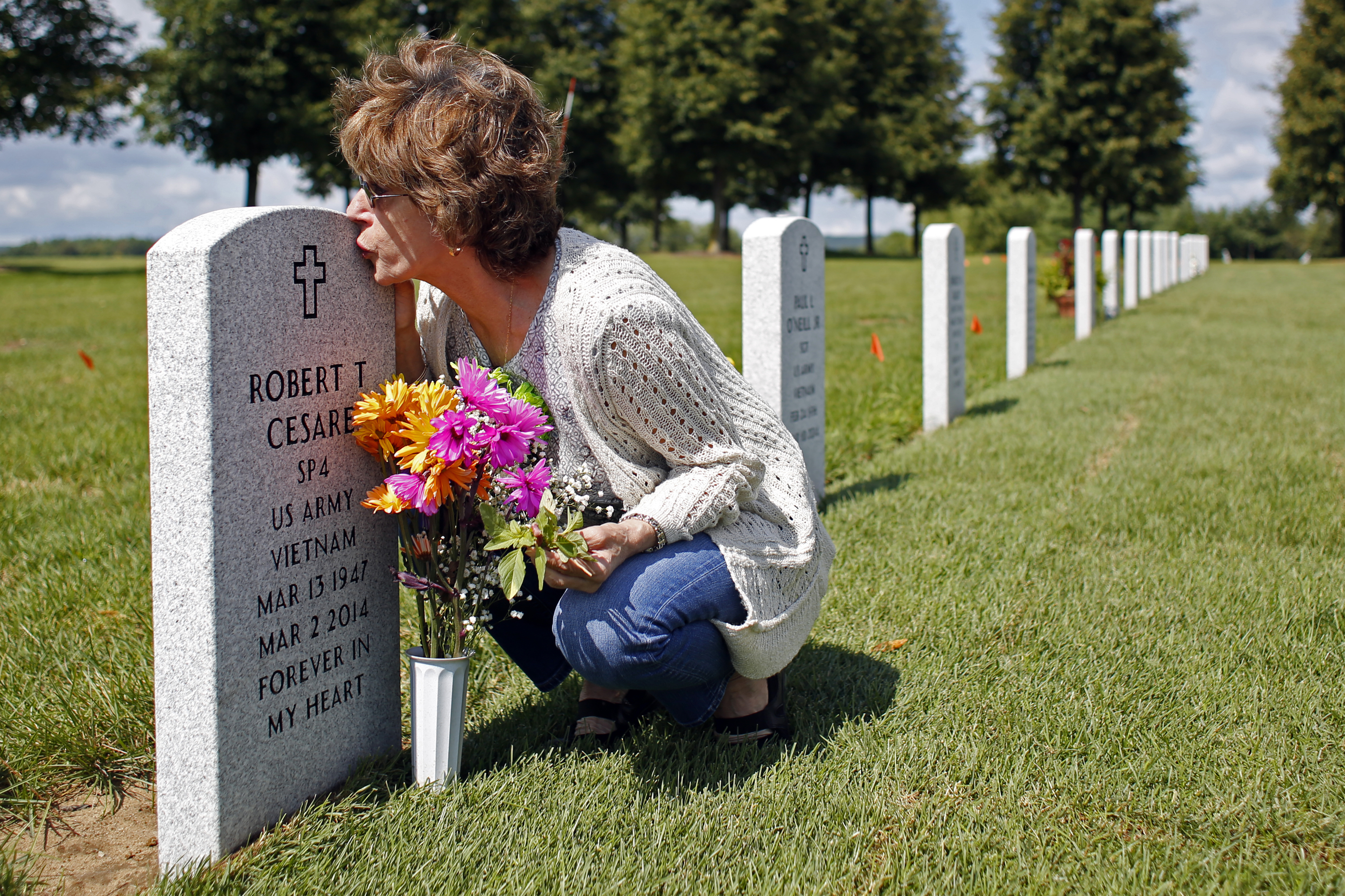 Francesca Cesare kisses her late husband's tombstone  on Thursday, August 14, 2014 in Saratoga National Cemetery in Saratoga, N.Y.  Robert died in 2014 of three different types of cancer related to exposure to Agent Orange while serving in the United States Army during the Vietnam War.