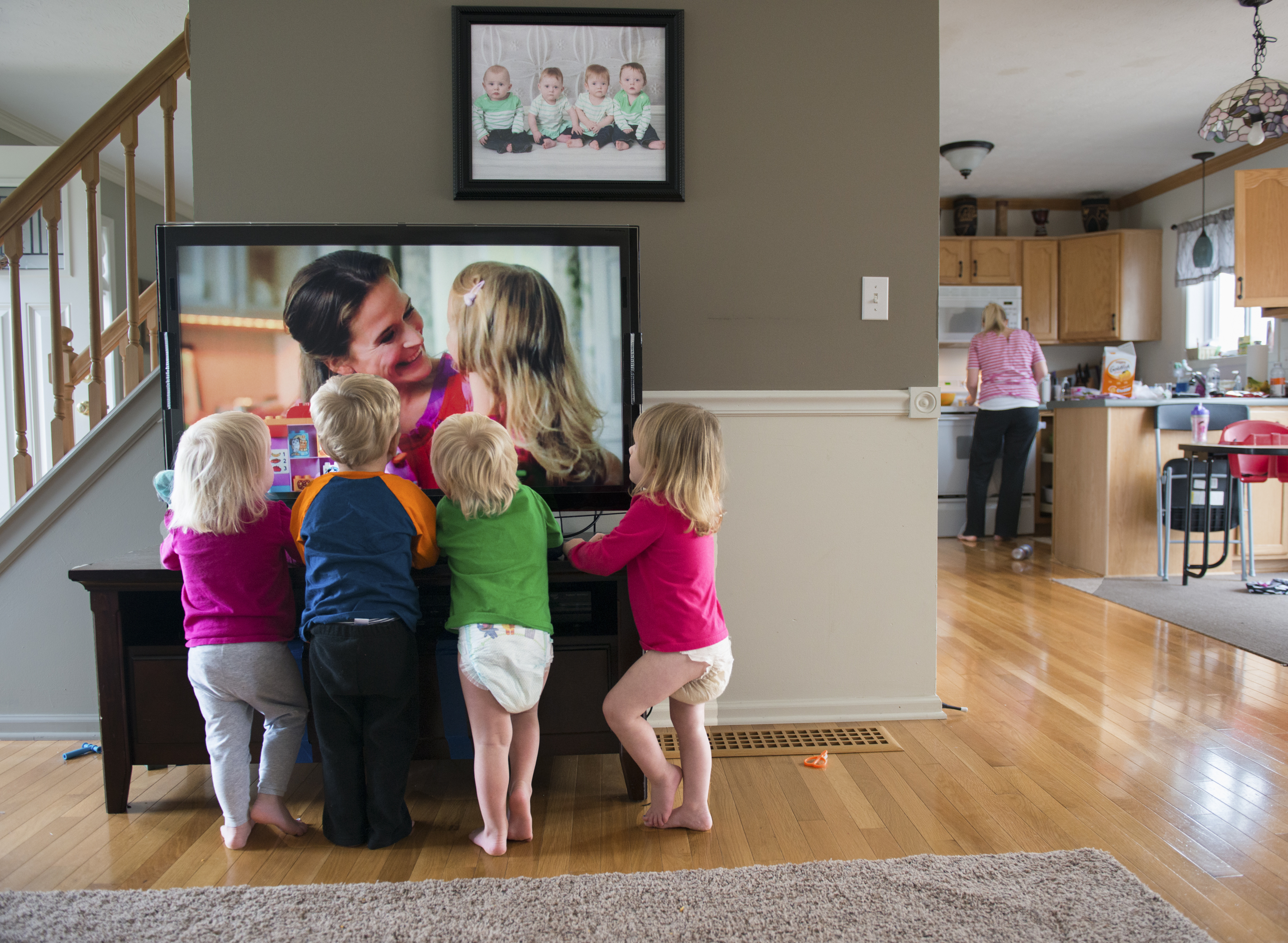The Larson quadruplets (Left to Right) Ashlyn, Brody, Cooper, and Kylie watch television as Courtney prepares a snack for them in the kitchen. Courtney often turns on the television to distract the children while she prepares food or does chores around the house. Nov. 16, 2014.