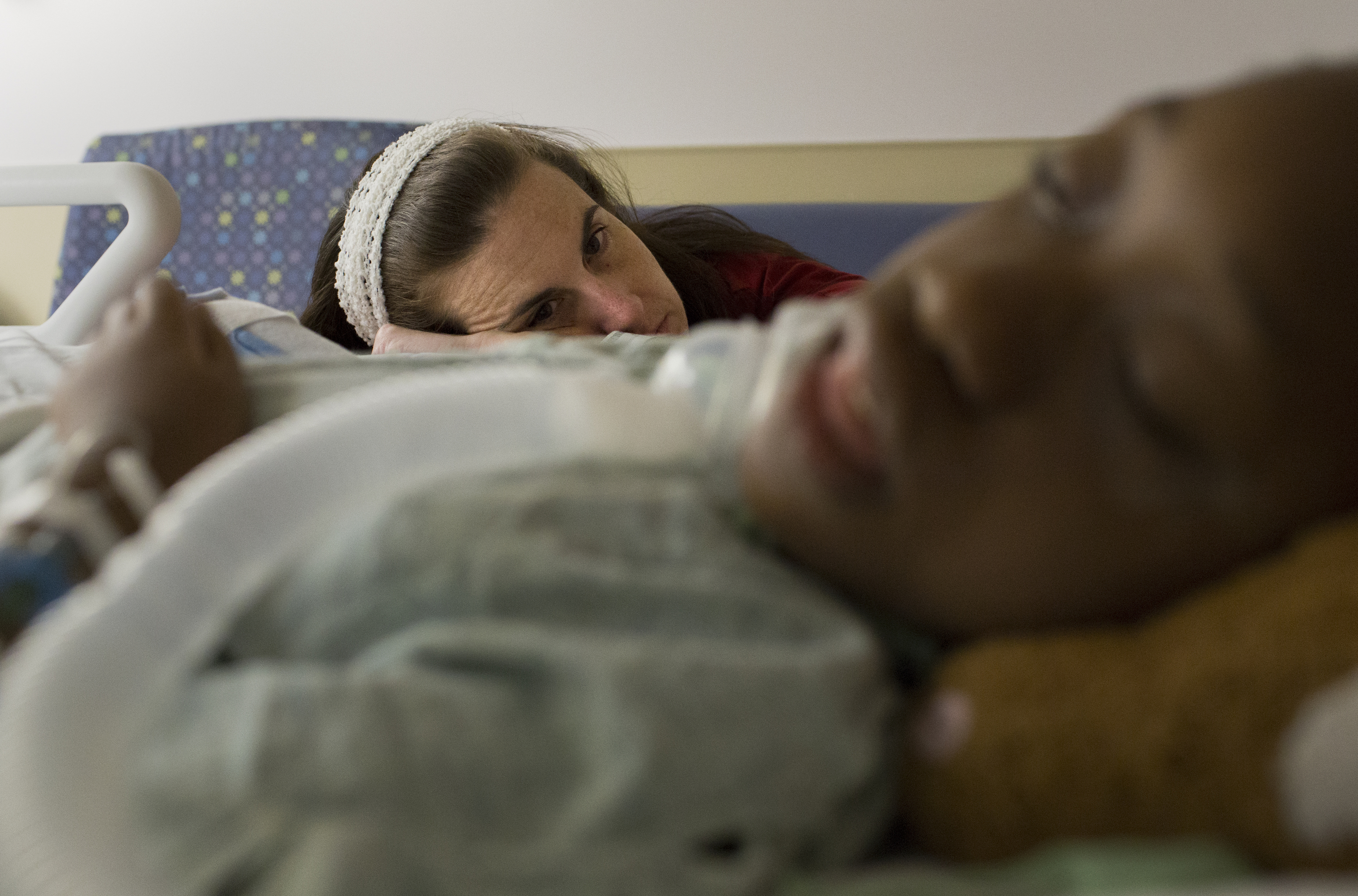 Chaney Roko looks over her sedated adopted daughter, Mary Roko, 9, inside the Intensive Care Unit of the Strong Memorial Hospital on Monday, Sept. 14, 2015 in Rochester, N.Y.  Mary, who suffers from scoliosis was given morphine after having back surgery that would correct her spine.