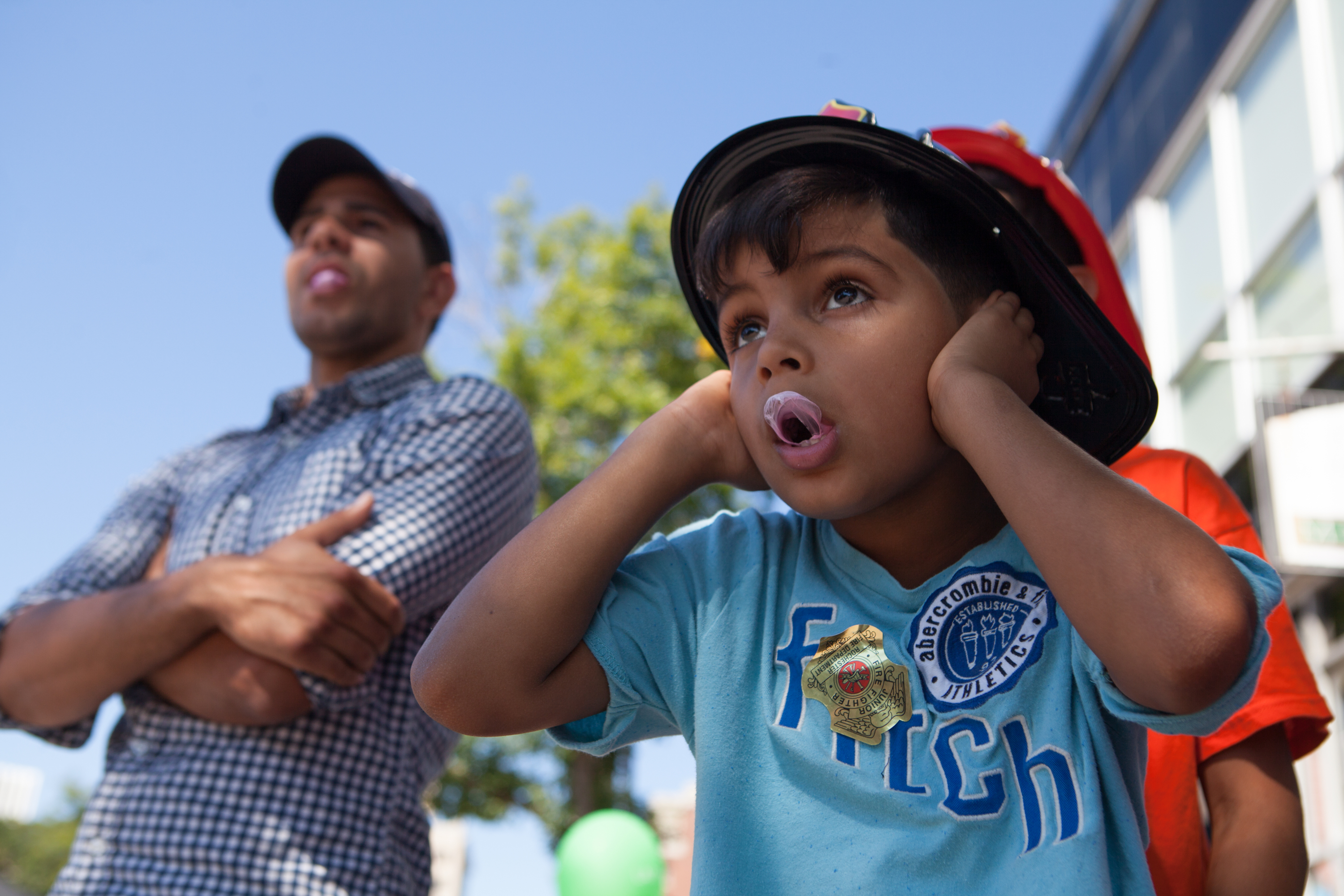 Jahdiel Marrero, 8, of Rochester, covers his ears as fire trucks blare their horns during the annual Rochester Labor Day parade along East Avenue in Rochester, N.Y., on Sept. 5, 2016. The parade featured union workers, public officials, and local first responders, among others.