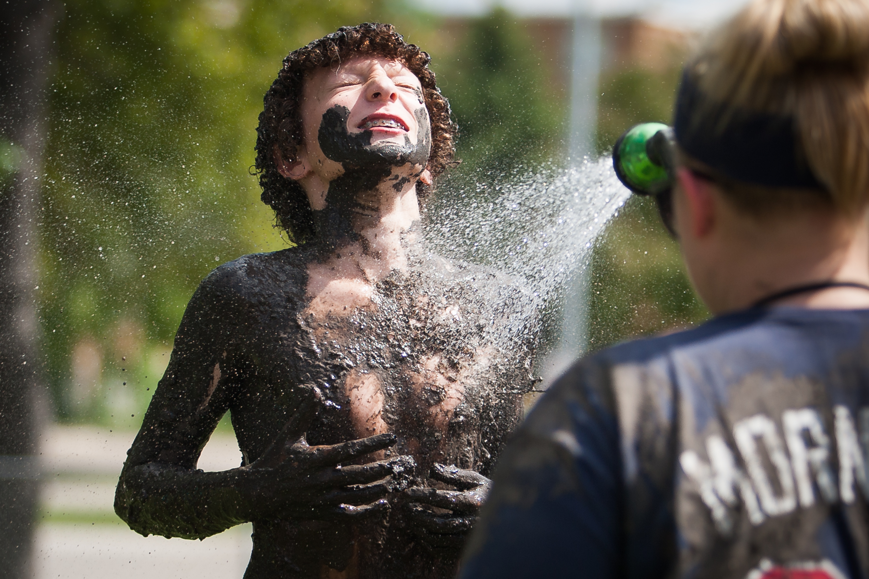 Theo Sum gets sprayed down after participating in International Mud Day at the University Children's Learning Center at the University of North Dakota on June 29, 2016 in Grand Forks, N.D.