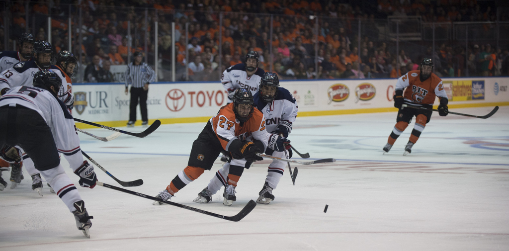 Alex Perron-Fontaine (#27) of the Rochester Institute of Technology Tigers fights for a puck against a member of the University of Connecticut Huskies hockey team, at Blue Cross Arena, on Oct. 15, 2016, in Rochester, N.Y. The game ended in an overtime tie, 1-1.