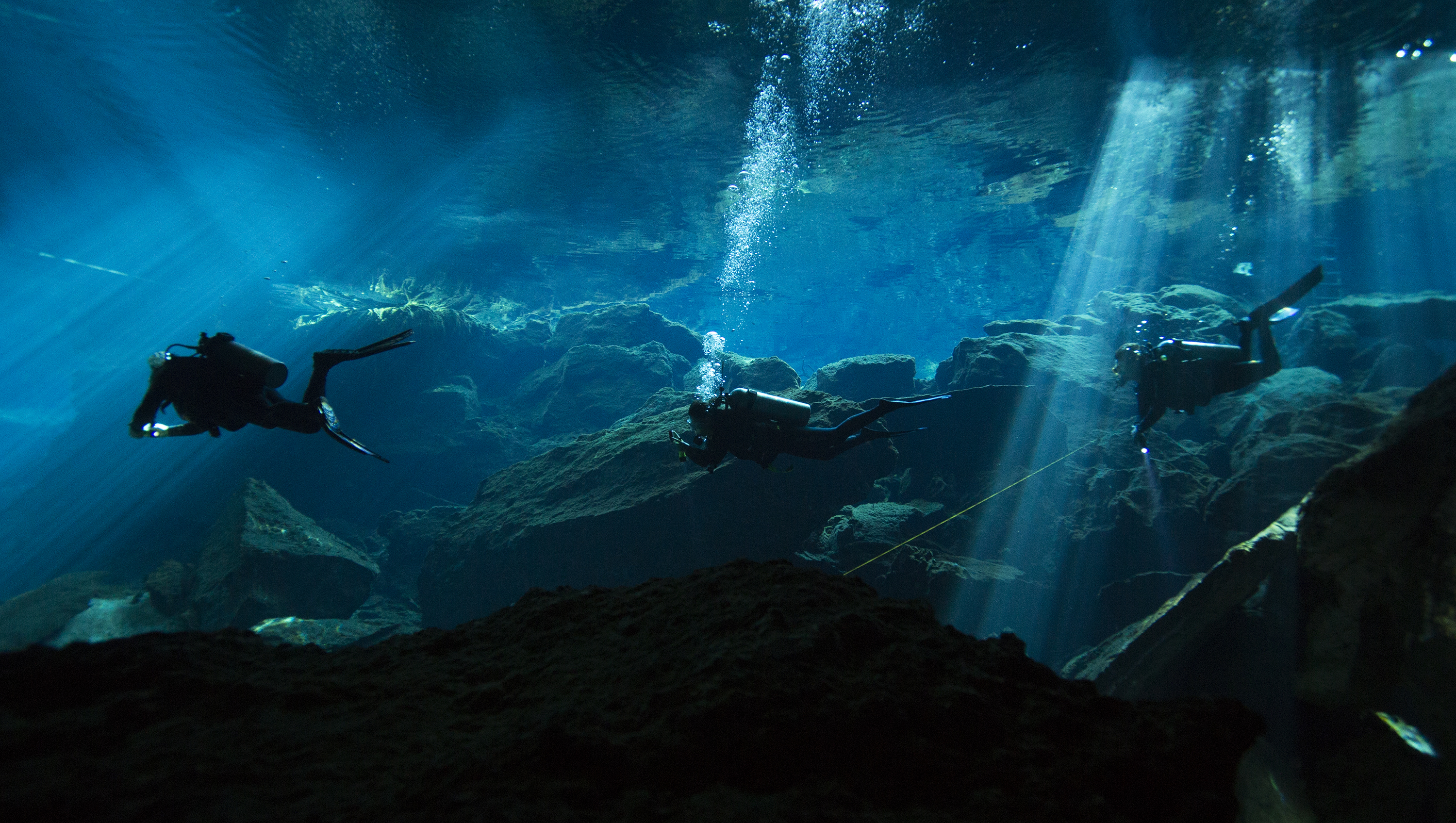 Three divers enter Hermano Pequeno cenote at Chauc Mool, on Jan. 11, 2017, in Quintana Roo, MX.  Cenotes are sinkholes made from collapsed limestone and filled with water, which contain caverns and well as caves.